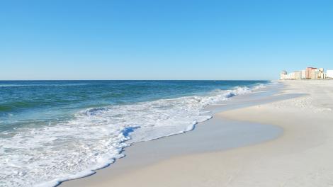 Waves rolling in over the wide, white-sand beach