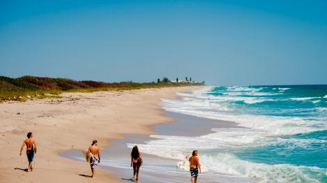 Surfers strolling along one of the area’s 115 kilometers of beaches