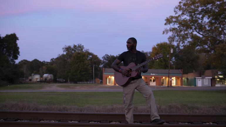 在杰克逊的夜色中弹奏吉他的 Cedric Burnside 在杰克逊的夜色中弹奏吉他的 Cedric Burnside