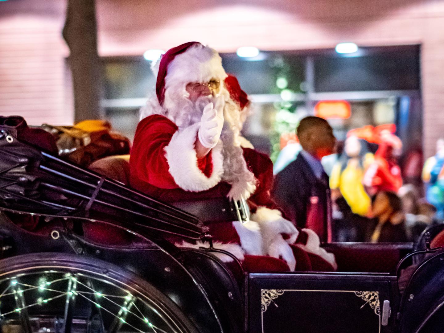Um homem vestido de Papai Noel acenando para o público na Candy Cane Lane Parade em Visalia, Califórnia