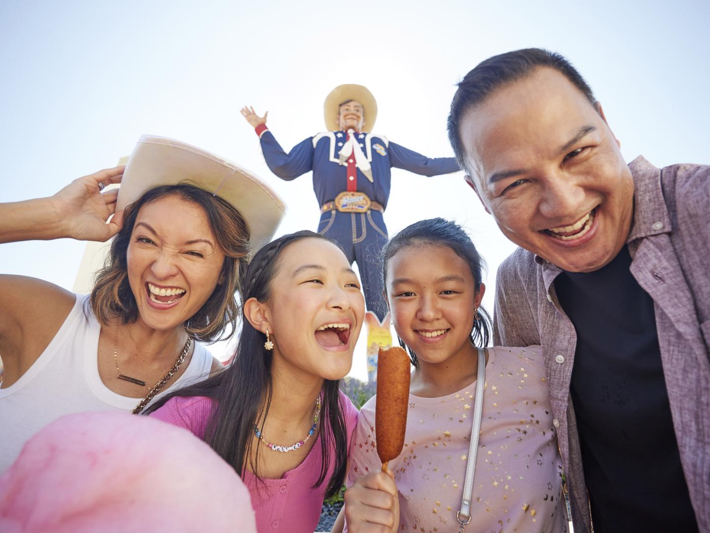 Family poses with statue Big Tex at the Texas State Fair in Dallas, Texas