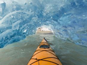 Surreal view surrounding a kayaker navigating through a cave at Mendenhall Glacier Lake Surreal view surrounding a kayaker navigating through a cave at Mendenhall Glacier Lake
